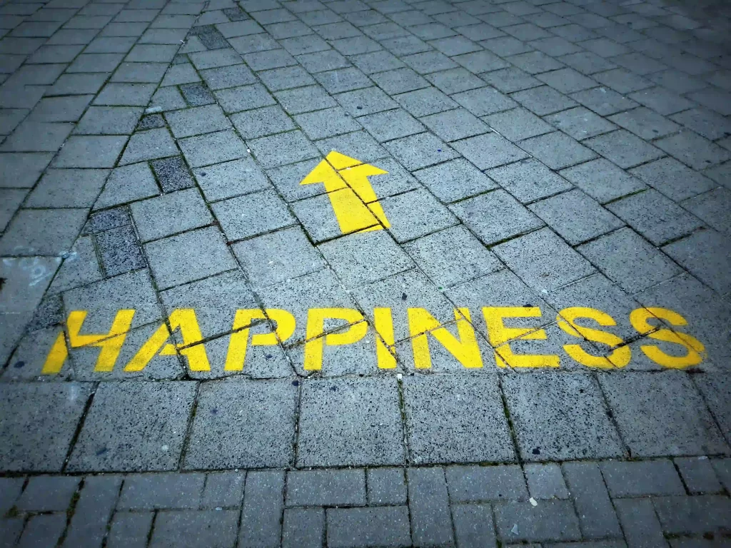 Happiness' painted on a sidewalk, related to an article on boosting joy